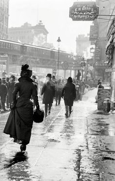 An old photograph of a woman walking down a city street.