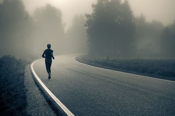 A person is running down a road on Valentine's Day in the fog, wearing stylish shoes.