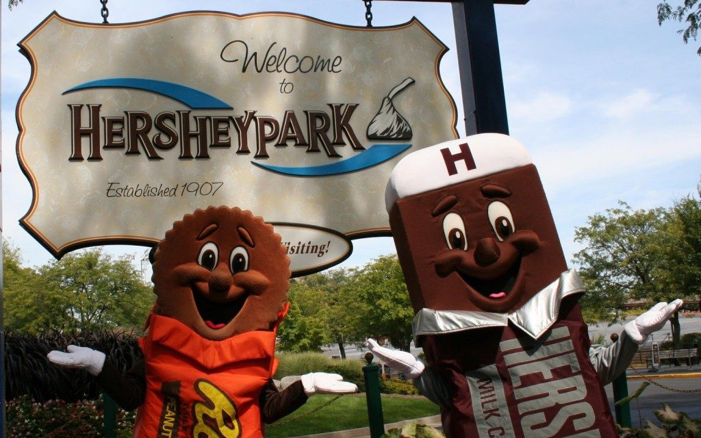 Two hershey park characters standing in front of a sign.