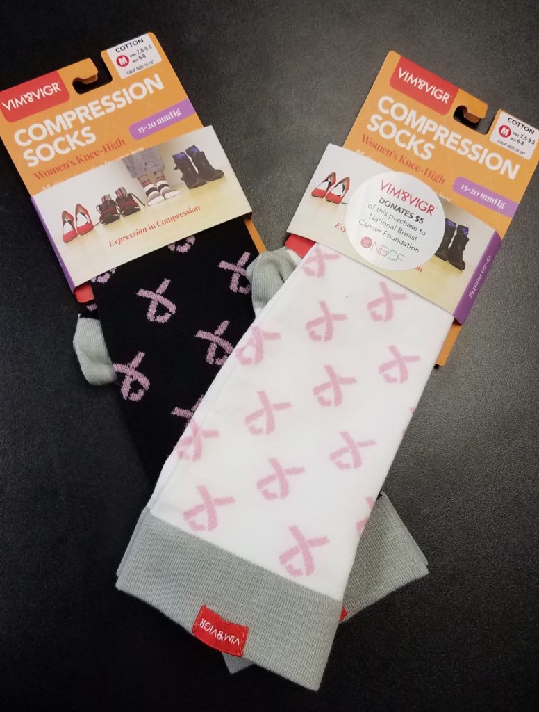 Two packages of compression socks with pink and white designs promoting breast cancer awareness.